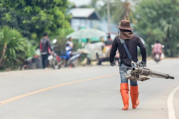 Человек затуманивает химикат, чтобы устранить комаров на улице — стоковое фото
