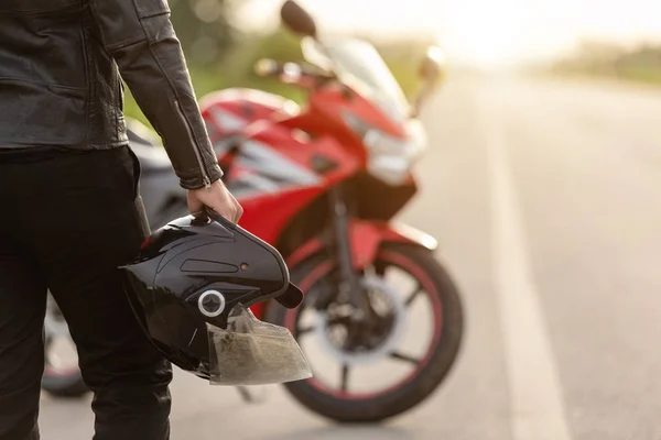 Schöner Motorradfahrer trägt Lederjacke und hält Helm auf — Stockfoto
