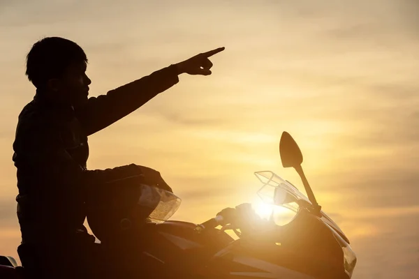 Schöner Motorradfahrer zeigt mit dem Finger in den Himmel — Stockfoto