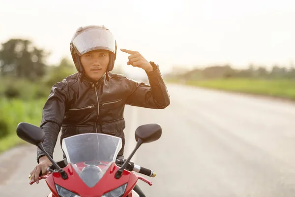 Schöner Motorradfahrer trägt Lederjacke und hält Helm auf — Stockfoto