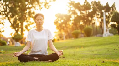 Güzel Asyalı kadın parkta yoga egzersizi yapıyor.