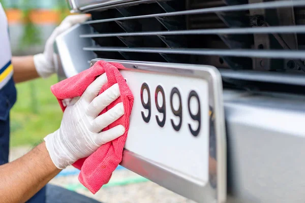 Man using red cloth to cleaning front car plate number — Stock Photo, Image
