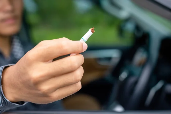 Joven sentado en el coche y destruir el cigarrillo a mano. Detente. — Foto de Stock