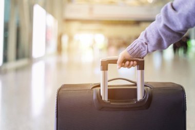 Genç turist havaalanında yürüyor ve bavullarını çekiyor.