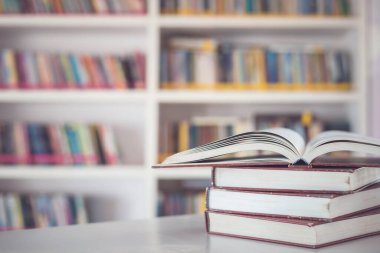 Kütüphane odasındaki masanın üstündeki kitap yığınını kapat ve kitaplık arkaplanının bulanık alanını kapat