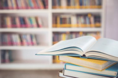 Kütüphane odasındaki masanın üstündeki kitap yığınını kapat ve kitaplık arkaplanının bulanık alanını kapat