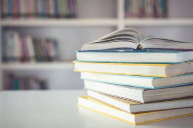 Kütüphane odasındaki masanın üstündeki kitap yığınını kapat ve kitaplık arkaplanının bulanık alanını kapat