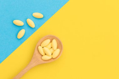 Sarı arka planda tahta kaşıkla sarı ilaç.