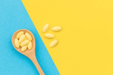 Sarı arka planda tahta kaşıkla sarı ilaç.