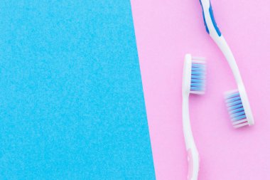 Üst görünüm pembe arkaplan üzerinde yeni pembe ve mavi diş fırçası metin veya tasarım için kopyalama alanı ile.