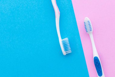 Üst görünüm pembe arkaplan üzerinde yeni pembe ve mavi diş fırçası metin veya tasarım için kopyalama alanı ile.