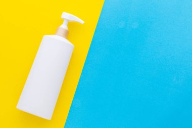 Sarı arka planda şampuan ya da sabun için kullanılan boş beyaz plastik pompa şişesi