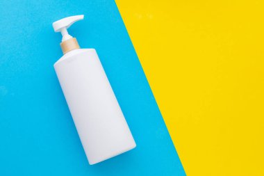 Mavi arka planda şampuan ya da sabun için kullanılan boş beyaz plastik pompa şişesi