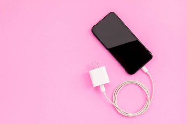 Metin veya tasarım için kopyalama alanı olan beyaz şarj cihazlı üst görünüm yeni akıllı telefon