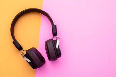 Üst görünüm siyah kulaklık ya da parlak renk arkaplanlı kulaklık. Metin veya tasarım için boşluk kopyala