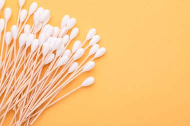 Sarı arka planda kulakları temizlemek için pamuk tomurcuğu