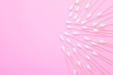 Pembe arka planda kulakları temizlemek için pamuk tomurcuğu