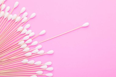 Pembe arka planda kulakları temizlemek için pamuk tomurcuğu