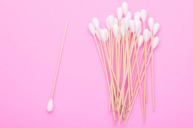 Pembe arka planda kulakları temizlemek için pamuk tomurcuğu