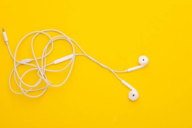 Sarı arka planda beyaz kulaklık. Metin veya tasarım için boşluk kopyala