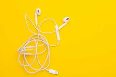 Sarı arka planda beyaz kulaklık. Metin veya tasarım için boşluk kopyala