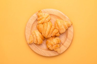 Sarı arka planda ahşap kapta mini kruvasan. Kopyalama alanı olan yiyecek kavramı