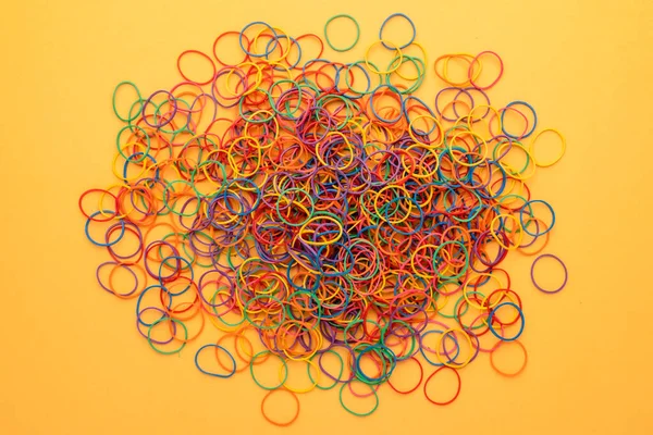 Top view Elastic band rubber, multicolor rubber bands on yellow backgrounds