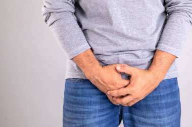 Pain on penis concept : Man use his hands to press on his penis on grey background