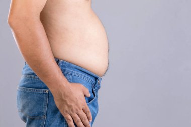 Ayakta duran şişman adamı kapat ve göbek atölyesindeki gri arkaplanda metin ya da tasarım için fotokopi çekimini göster. Şişman insanlar ve sağlıklı kavram