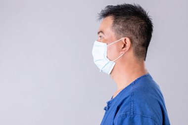 Tay çiftçisinin portresi, gri arka planda virüs çekimini önlemek için koruyucu yüz maskesi takıyor.