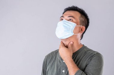 Taylandlı hasta portresi koruyucu yüz maskesi takıyor ve boynundaki stüdyoya dokunuyor.