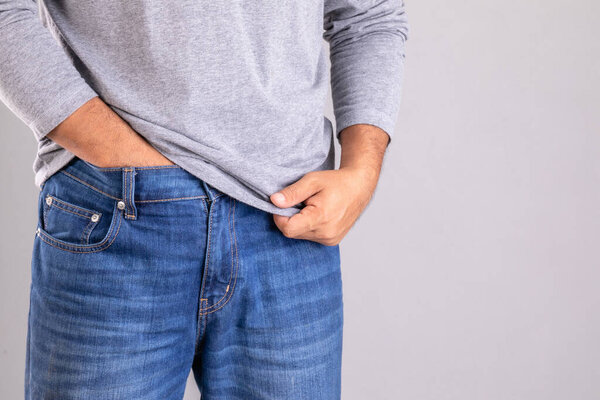Itchy or Tinea Cruris concept. Man use hand scratching under his pant studio shot on grey background