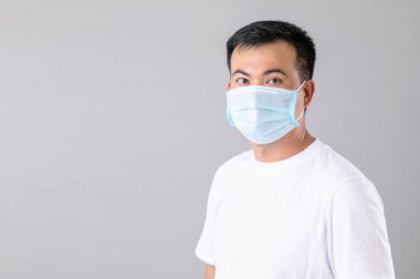 Gri arka planda virüs çekimini önlemek için Taylandlı adamın koruyucu yüz maskesi taktığı portre