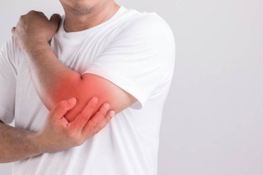 Dirsek ağrısı kavramı: dirseğini tutan ve acı hisseden bir adam. Stüdyo görüntüsü gri arkaplanda izole edildi ve metin için kopyalama alanı
