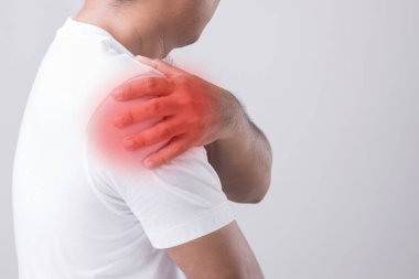 Omuz ağrısı kavramı: bir adamın omzuna dokunması ve acı hissetmesi. Stüdyo görüntüsü gri arkaplanda izole edildi ve metin için kopyalama alanı