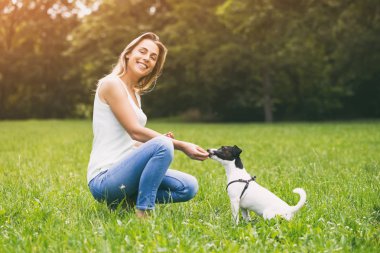 Güzel bir kadın onun sevimli köpek Jack Russell Terrier doğal besleme sahiptir. Görüntü kasten tonda.