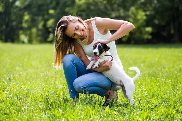 美しい女性は 彼女のかわいい犬のジャック ラッセル テリアで自然の中の時間を費やして楽しんでいます — ストック写真