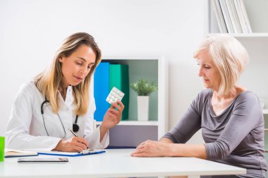 Kadın doktor onun sağlık sorunları için üst düzey hastasını reçete yazma.