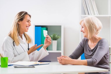 Kadın doktor hap onun sağlık sorunları için üst düzey hastasını veriyor.