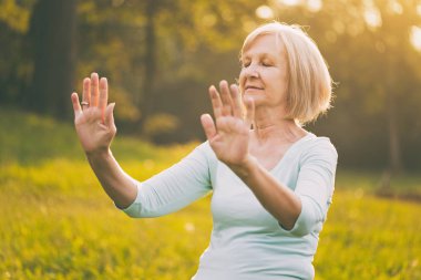 Kadın kıdemli Egzersiz Tai Chi doğada sahiptir. Görüntü kasten tonda.