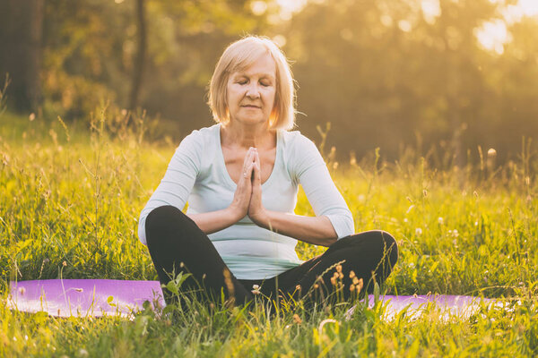 Senior woman enjoys meditating  in the nature.Image is intentionally toned.