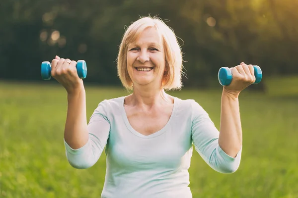 Sportieve Senior Vrouw Oefenen Met Gewichten Buiten Afbeelding Opzettelijk Afgezwakt — Stockfoto