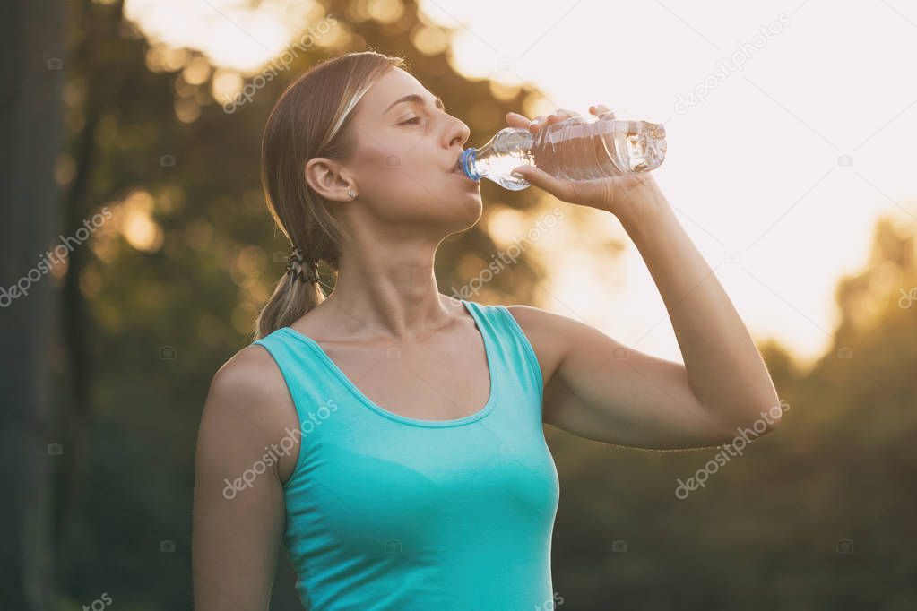 Beautiful woman enjoys drinking water during exercise.Image is intentionally toned.