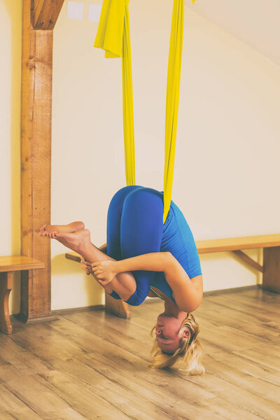 Woman doing aerial yoga in the fitness studio.Image is intentionally toned.