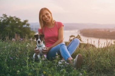 Güzel kadın köpeğini Jack Russell Terrier arkasında cityscape ve nehir manzaralı açık ile zaman geçirmekten hoşlanıyor. Görüntü kasten tonda.