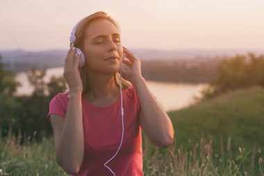 Güzel kadın sahiptir dinleme müzik arkasında cityscape ve nehir manzaralı açık. Görüntü kasten tonda.
