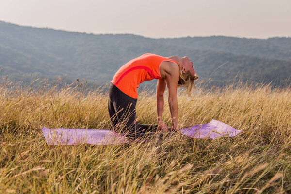 Beautiful woman doing yoga in the nature,Ustrasana advanced/Camel pose, palms set against feet.Image is intentionally toned.