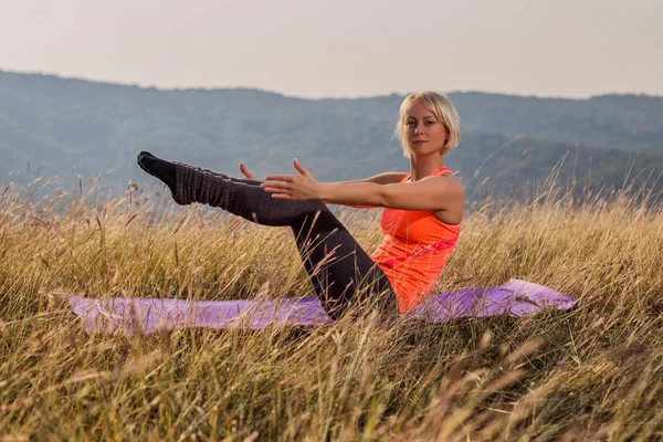 美丽的女人在大自然中做瑜伽 Navasana 小船姿势 图像是故意色调 — 图库照片