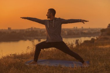 Şehir Manzaralı, Virabhadrasana /Warrior Pose.Toned görüntü günbatımı üzerinde yoga yapan erkek.