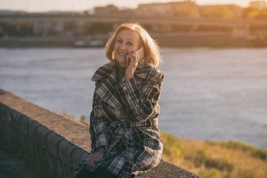 Otururken nehrin süre telefonda konuşurken kadın kıdemli. Tonlu görüntü.
